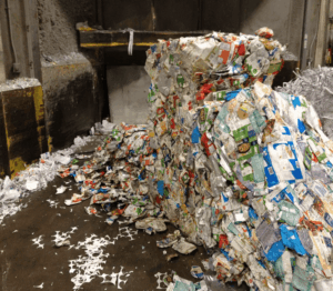 Bales of colourful cartons on the ground next to a baler at Winnipeg's sorting facility.