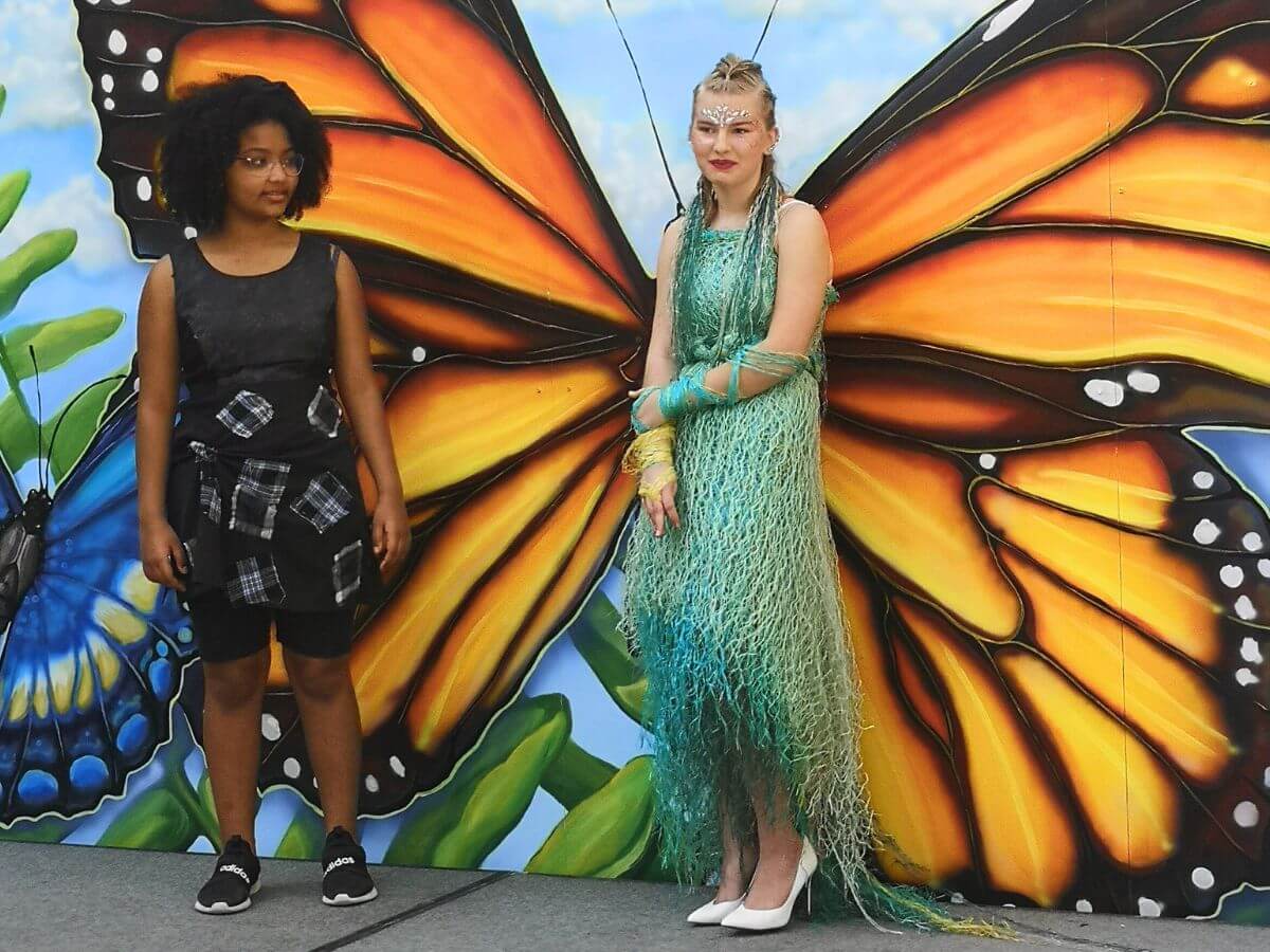 Manitoba student poses on stage at fashion show in a bright sea green dress made of baler twine and netting