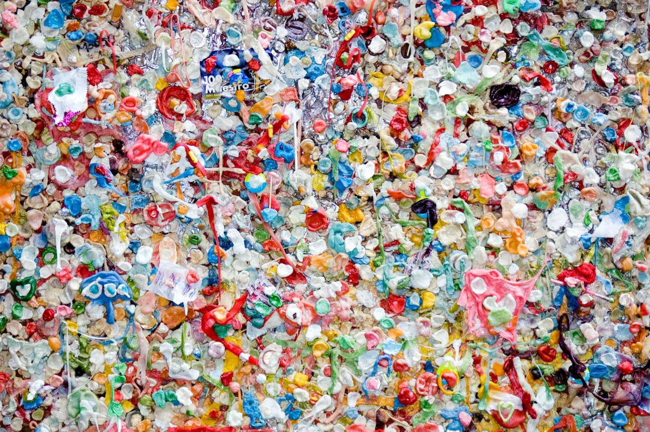 Crushed recycled plastic bottle caps and fragments in red, blue, green, yellow and white, seen from above.
